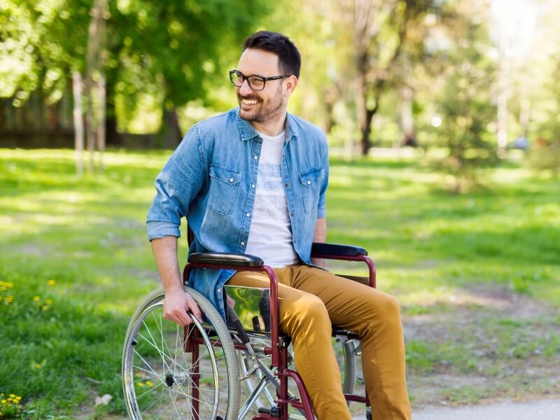 Smiling young positive handicapped man in wheelchair